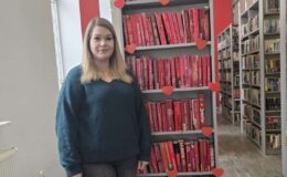 Mielna Matuszewska z Miejskiej Biblioteki Publicznej w Działdowie przy regale z książkowymi walentynkowymi propozycjami