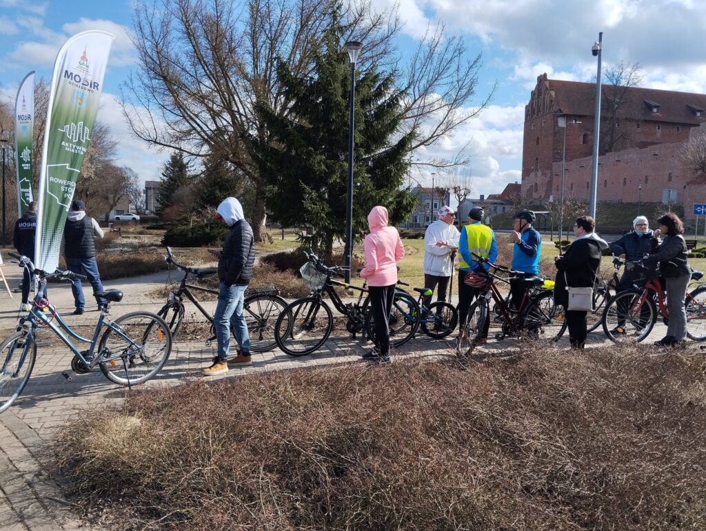 widać grupę osób stojącą z rowerami w kolejce