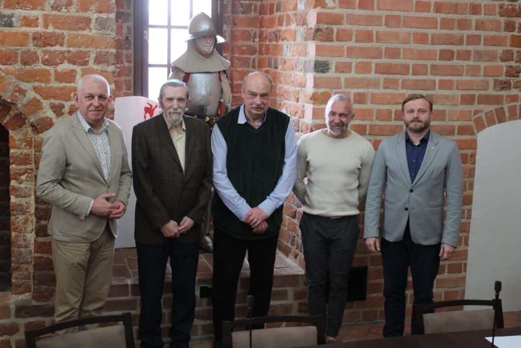 stoją w refektarzu burmistrz Grzegorz Mrowiński, Franciszek Skibicki, prof. Wojciech Polak, dr Szymon Drej i dyrektor muzeum Patryk Kozłowski