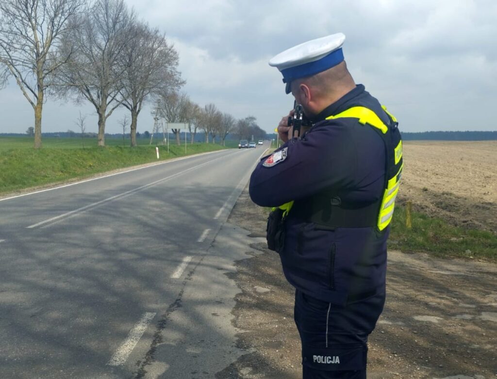 policjant stojący przy drodze z radarem, podczas pomiaru prędkości pojazdów