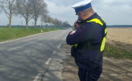 policjant stojący przy drodze z radarem, podczas pomiaru prędkości pojazdów