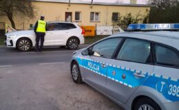 policjant badający trzeźwość kierowcy, na zdjęciu widać radiowóz i samochód osobowy / fot. policja
