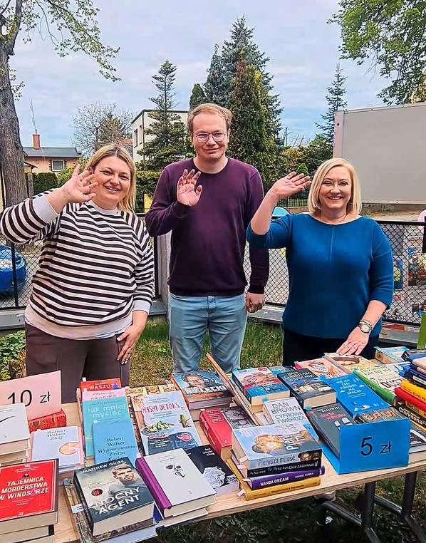 widać dwie kobiety i mężczyznę oraz stół z książkami