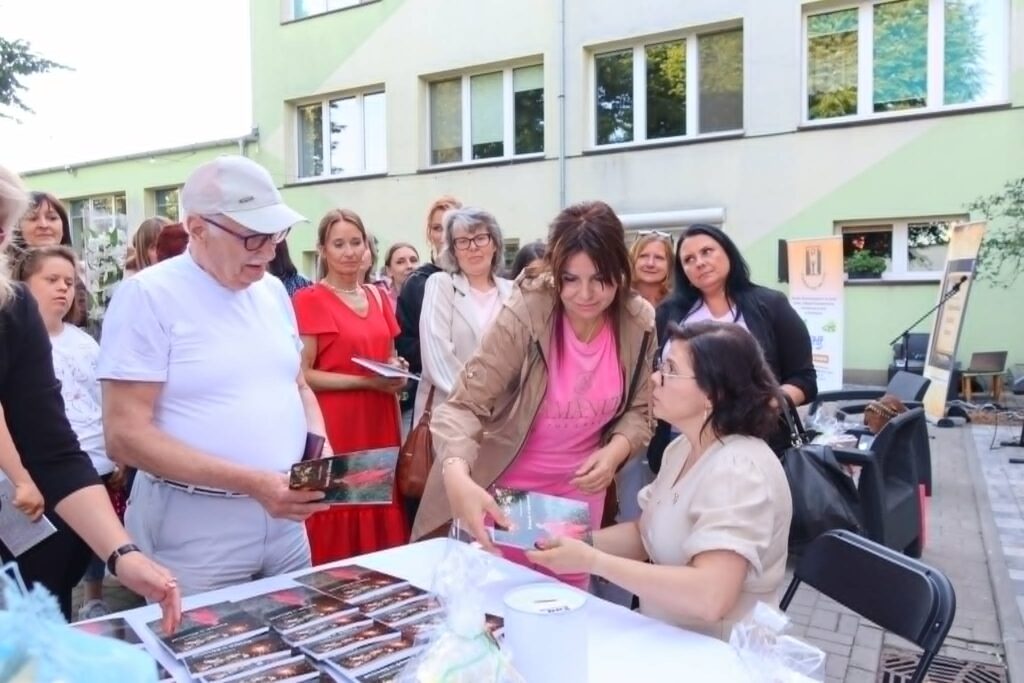 widać grupę osób, a poetka Joanna Śliwka wręcza egzemplarze swojej książki / fot. Jadwiga Smółka