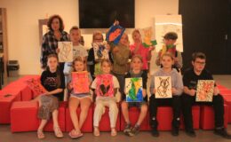 grupa dzieci prezentuje swoje prace wykonane podczas wakacyjnych zajęć w Muzeum Pogranicza