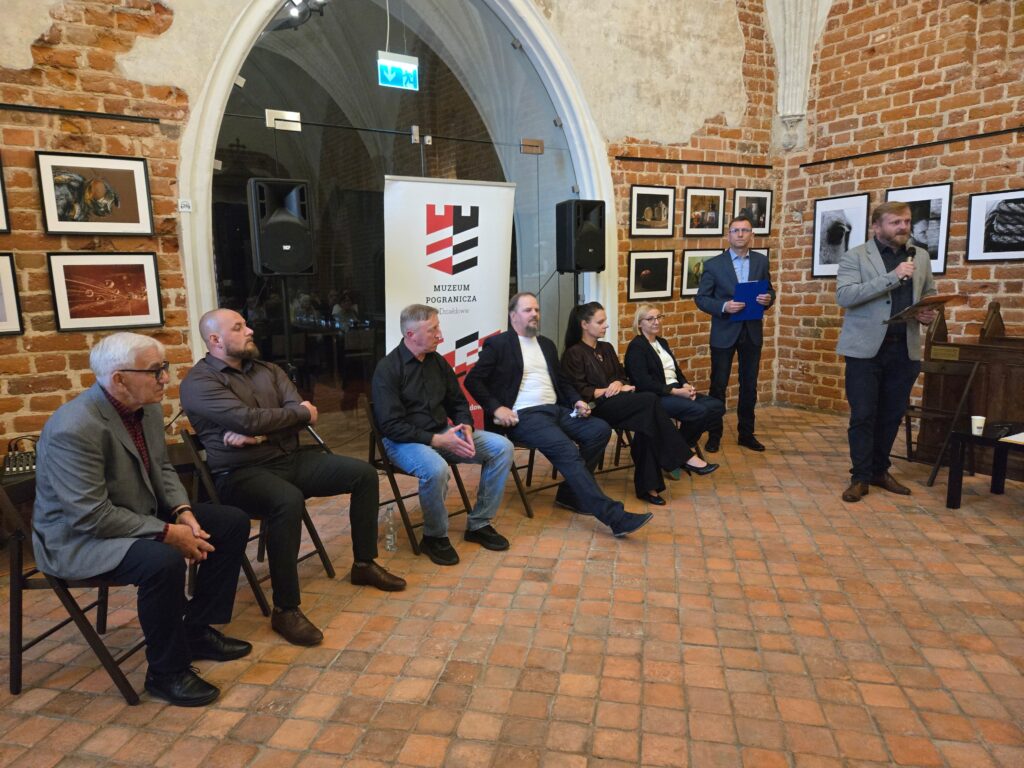 prowadzący spotkanie Piotr Kozikowski i artyści fotograficy w kaplicy zamkowej Muzeum Pogranicza w Działdowie