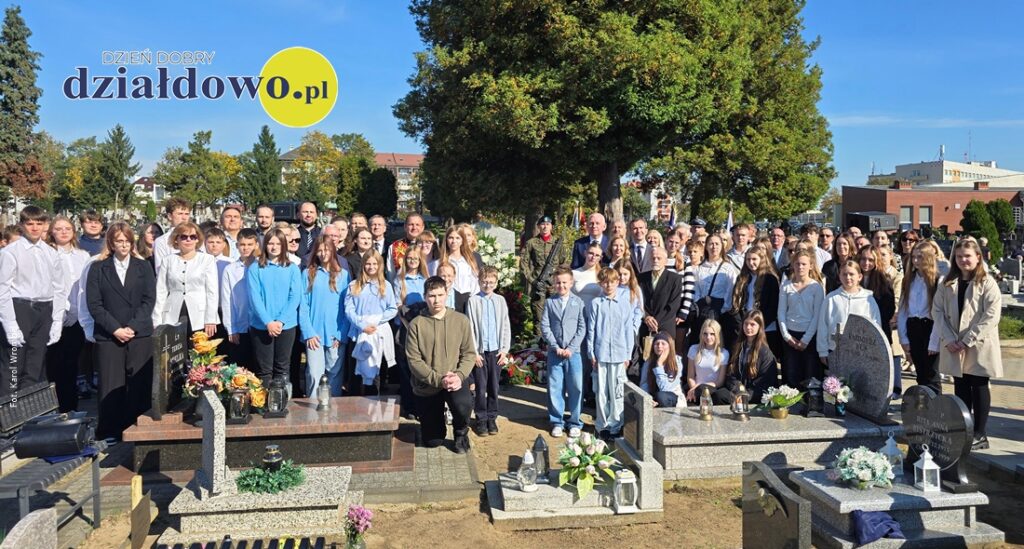 uczestnicy uroczystości, dzieci, młodzież, osoby dorosłe, kobiety, mężczyźni stoją przy pamiątkowej tablicy na cmentarzu parafialnym pw. Św. Wojciecha w Działdowie